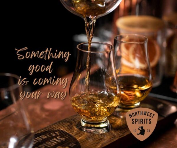 Golden whiskey fills a tasting glass on a wooden board. Northwest Spirits logo near. "Something good is coming your way."