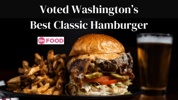 A close-up of "Washington's Best Classic Hamburger," featuring a beef patty, bacon, veggies, fries, and a beer.