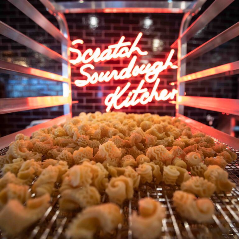 Fresh scratch-made sourdough pasta drying in front of neon “Scratch Sourdough Kitchen” sign at Von’s 1000Spirits