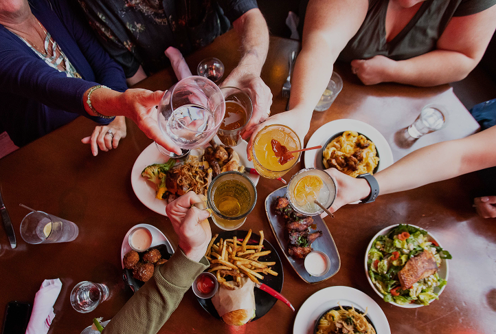 People toasting over a table full of plates of food