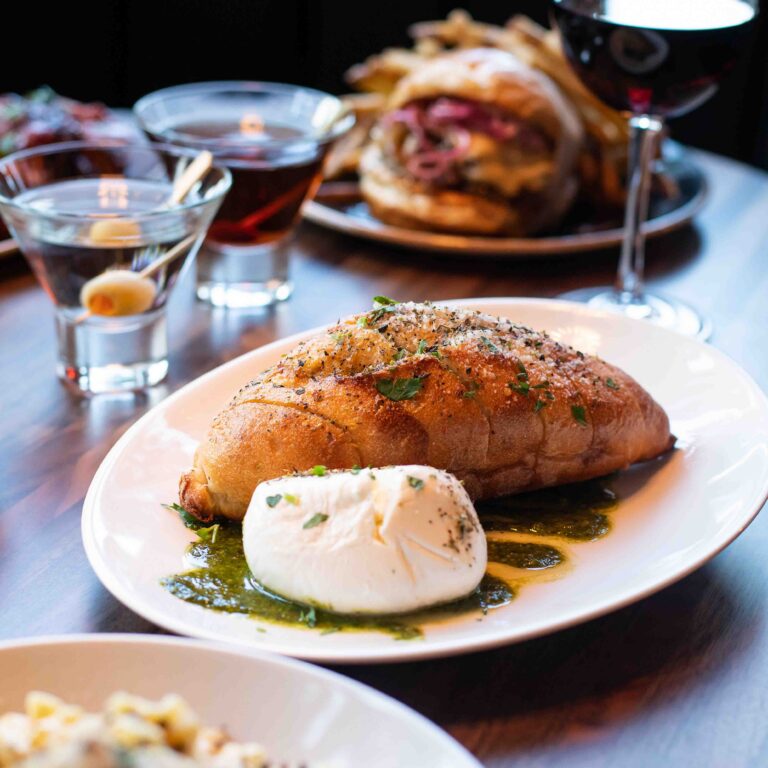 Sourdough bread with fresh burrata and herb oil served with martinis and burger at Von’s 1000Spirits Seattle