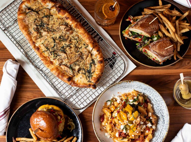 Scratch-made sourdough pizzas, pasta, burger, and cocktails on table at Von’s 1000Spirits